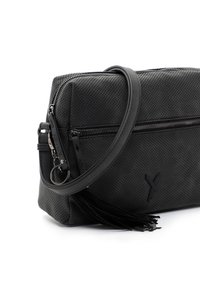 Czarna perforowana torebka z teksturowaną powierzchnią, zamkiem błyskawicznym, regulowanym paskiem na ramię oraz ozdobnym frędzlem.