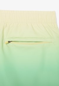 Shorts con gradiente verde chiaro e giallo, dotati di una cintura elastica e una tasca con zip sul retro per riporre in sicurezza gli oggetti.