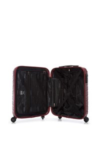 Maleta de carcasa dura en rojo oscuro, con una superficie texturizada, interior negro con un patrón geométrico y compartimentos con cremallera.