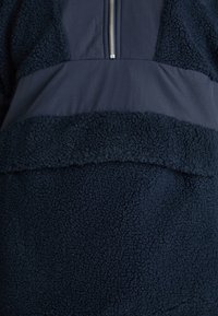 Marineblauw pullover met een gestructureerd, pluizig fleece ondergedeelte en een glad bovenpaneel met een kwartrits.