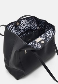 Large black leather tote bag with textured exterior, leopard-print lining, zip pocket, and magnetic closure. Adjustable shoulder straps included.