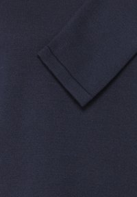 Pull en maille bleu marine présentant une texture lisse, avec un détail de manchette pliée sur la manche. Coupe classique avec des accents côtelés.
