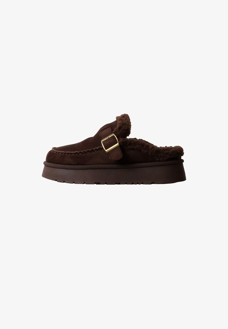 Chausson marron en daim à enfiler, avec semelle épaisse, doublure en fourrure, couture mocassin et bride réglable avec boucle dorée.