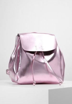 Glinsterende metallic roze rugzak met klep, trekkoordsluiting en verstelbare schouderbanden op een witte ondergrond.
