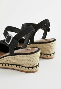 Sandales à talon en noir avec une semelle en jute de style espadrille, des brides en tissu, une boucle réglable et des coutures contrastées le long de la base.