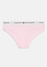 Rozā kokvilnas biksītes ar baltu elastīgu jostu, kurā ir uzraksts "TOMMY HILFIGER". Gluda tekstūra un klasiskas formas dizains.