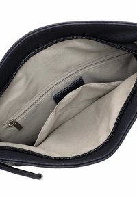 Intérieur d'un sac en cuir noir avec un revêtement beige clair, comportant une poche zippée et un compartiment ouvert pour l'organisation.