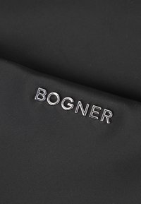 Tessuto nero con finitura testurizzata, caratterizzato dal logo "BOGNER" in argento metallizzato. Il design è minimalista con uno schema di colori ad alto contrasto.