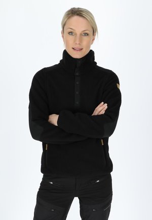 Zwarte fleecepullover met hoge kraag, drukknoopjes en contrasterende zwarte stofaccenten op de schouders. Gladde textuur, ritsen aan de zijkant.