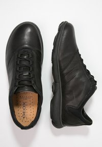 Black leather athletic shoes with a round toe, lace-up design, textured sides, and a cushioned insole; designed for breathability.