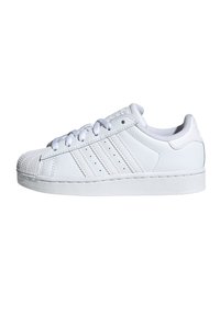 Bijele kožne tenisice s gumenim potplatom, teksturiranim vrhom i trima bočnim prugama. Imaju vezanje na vezice i glatke detalje na površini.