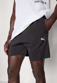 Sorte atletiske shorts i et let materiale, med en indsatslomme og et hvidt Puma-logo, designet til komfort og mobilitet.