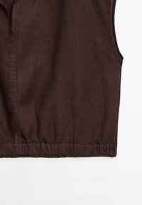 Brown sleeveless top made of linen; features a placket neckline and an elasticized hem for a relaxed fit. Textured fabric with a soft sheen.