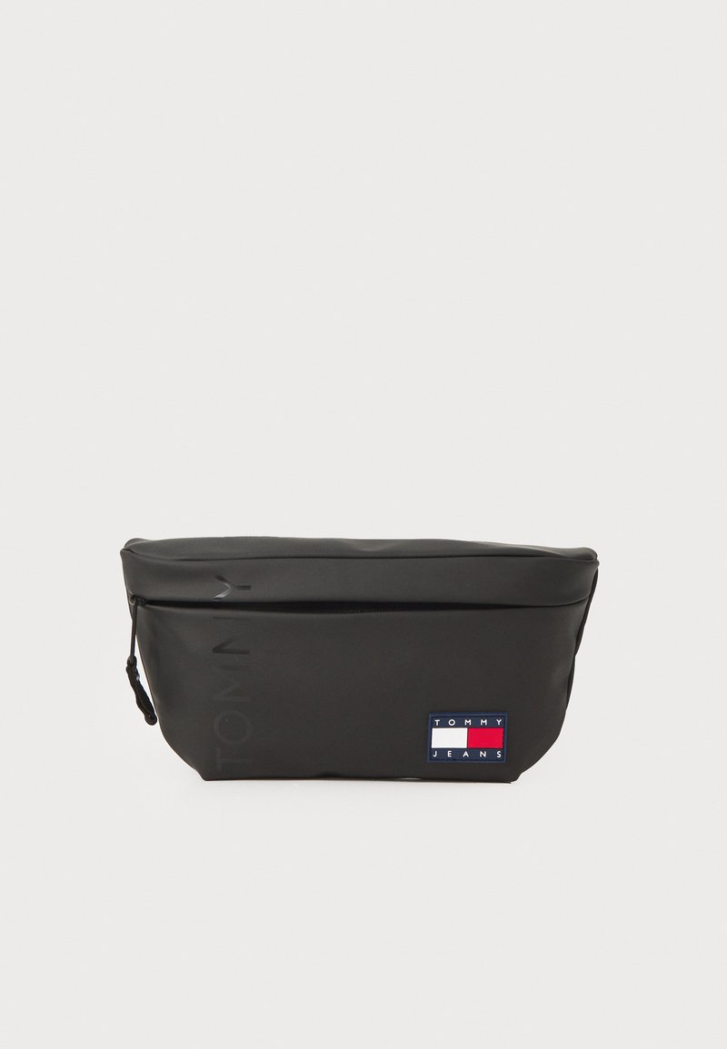 Svart glidelåsveske laget av teksturert materiale, med en logo i kontrasterende farger og et lite merke med merkeemblemet.