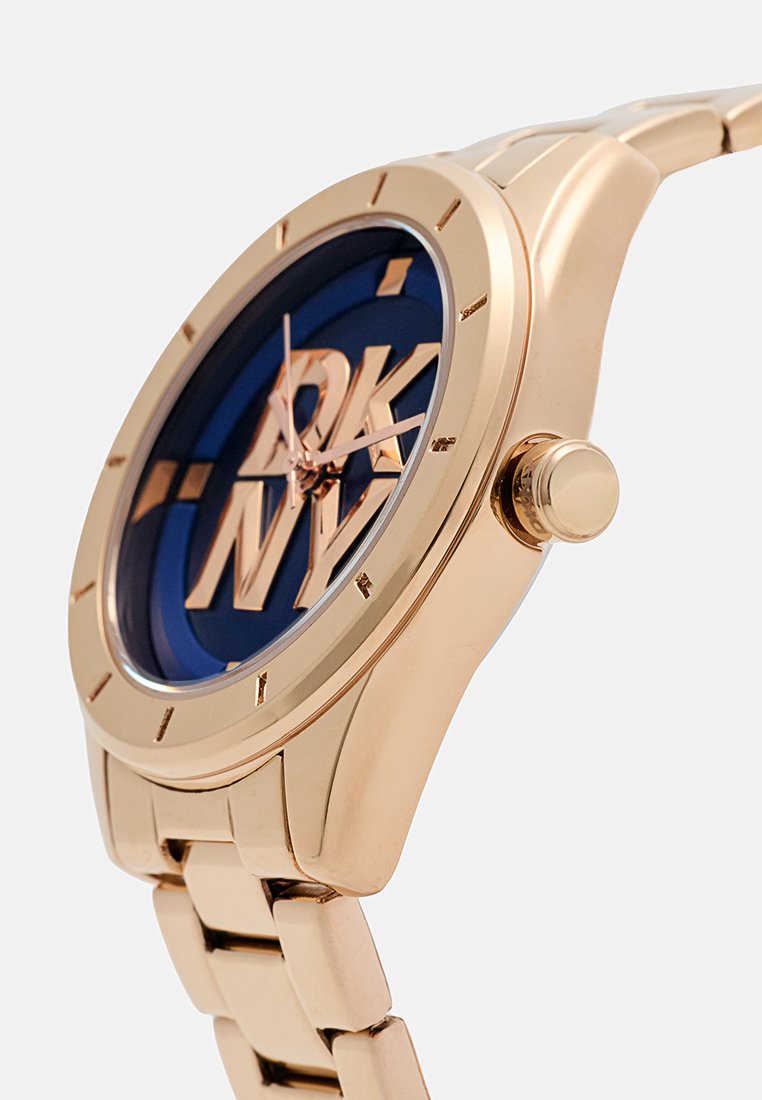 Złoty zegarek z metalową bransoletą z niebieską tarczą i dużym logo DKNY. Smukła koperta, okrąła tarcza oraz gładka bransoleta z polerowanym wykończeniem.