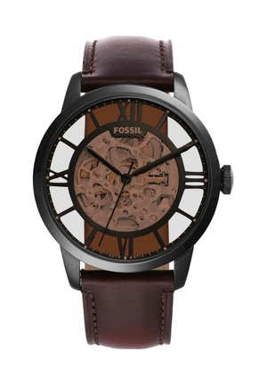 Fossil automatisch polshorloge met zwarte metalen kast, bruine leren band, skeleton wijzerplaat en zwarte Romeinse cijfer uurmarkeringen.