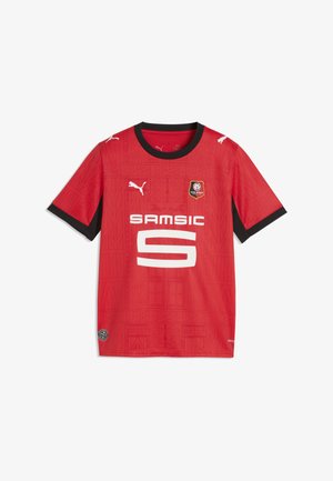 Czerwona koszulka piłkarska z krótkim rękawem z czarnym kołnierzykiem i krawędziami rękawów, logo Puma, herb Stade Rennais oraz biały napis sponsora Samsic.