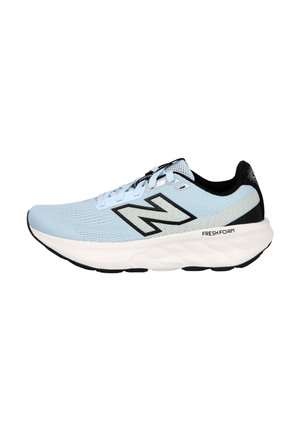Zapatilla deportiva azul claro con parte superior de malla, acentos negros, entresuela blanca y suela de goma firme. Presenta detalles de marca y diseño con cordones.