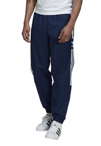 Tmavě modré joggingové kalhoty vyrobené z lehkého materiálu, s bílými bočními pruhy a elastickými lemy pro zúžený střih.