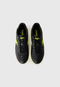 Black soccer shoes made of leather, featuring textured horizontal stripes and bright yellow accents on the sides and logo.