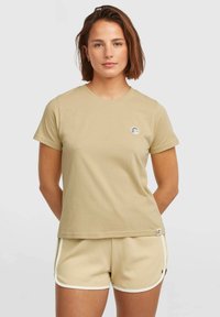 Beige short-sleeve t-shirt made of cotton, featuring a round neck and a small circular logo on the left chest. Paired with beige textured shorts.