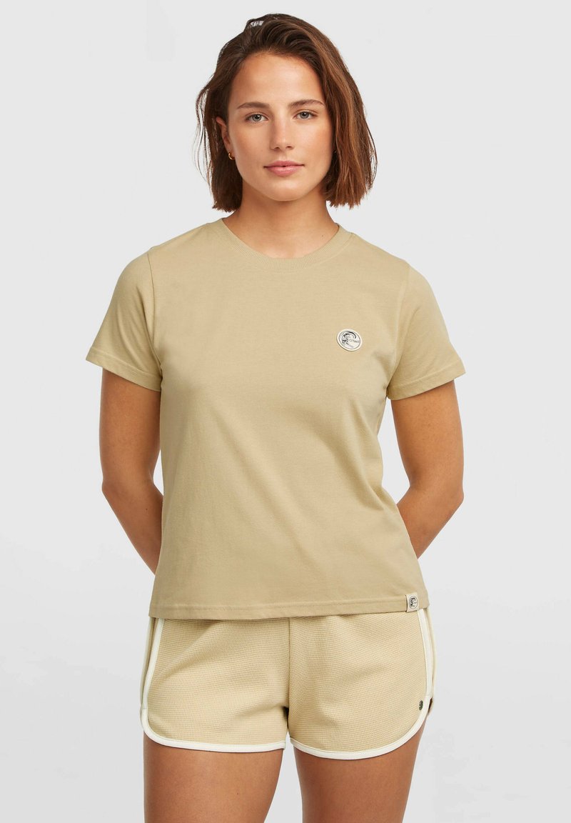Beige short-sleeve t-shirt made of cotton, featuring a round neck and a small circular logo on the left chest. Paired with beige textured shorts.