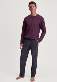 Lange mouwen paarse shirt gecombineerd met gemusterde marineblauwe pyjamabroek met geometrische ontwerpen. Lichtgewicht stof met een elastische tailleband.