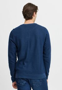 Felpa blu navy con tessuto testurizzato, colletto rotondo e maniche lunghe. Presenta un bordo e polsini a costine, progettata per una vestibilità rilassata.