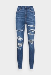 Ripped blå denim högmidjade skinny jeans med slitna detaljer, som visar upp trasiga kanter och en åtsittande silhuett.