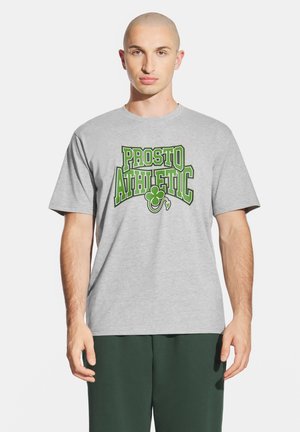 Szara bawełniana koszulka z zielonym nadrukiem tekstowym "PROSTO ATHLETIC" i wzorem koniczyny. Luźny krój i krótkie rękawy.