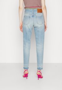 Ljusblå högmidjade jeans med rak passform, som har en beige läderlapp på bakre midjebandet och två bakfickor.