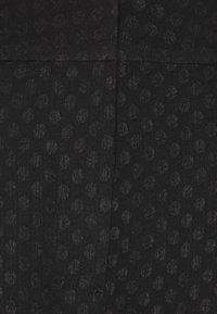 Schwarzer Stoff mit einem strukturierten Muster aus kleinen Kreisen. Die Oberfläche ist glatt mit einem leichten Glanz und zeigt subtile Tiefen im Design.