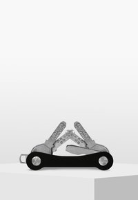 Multi-tool avec une poignée noire et des lames en acier inoxydable argentées. Les lames ont des prises texturées et divers outils pour une utilisation polyvalente.