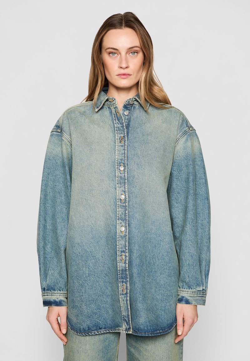 Camicia di jeans in gradiente blu chiaro, con chiusura a bottoni frontale, colletto a punta e vestibilità oversize con maniche lunghe e orli a sbuffo.