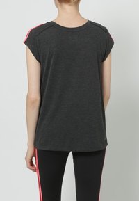 Camiseta de manga corta gris oscuro con rayas laterales rosas, hecha de una tela suave, con un corte relajado y escote redondeado.
