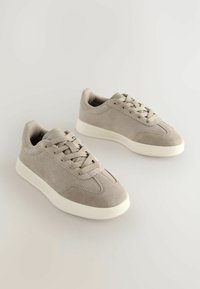 Grå ruskind sneakers med en glat hvid gummisål, rund tå og snørebåndsdesign med matchende snørebånd.