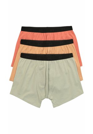 Tre par herreboxershorts i beige, lys orange og koralfarver med sorte elastiske taljebånd stablet oven på hinanden.