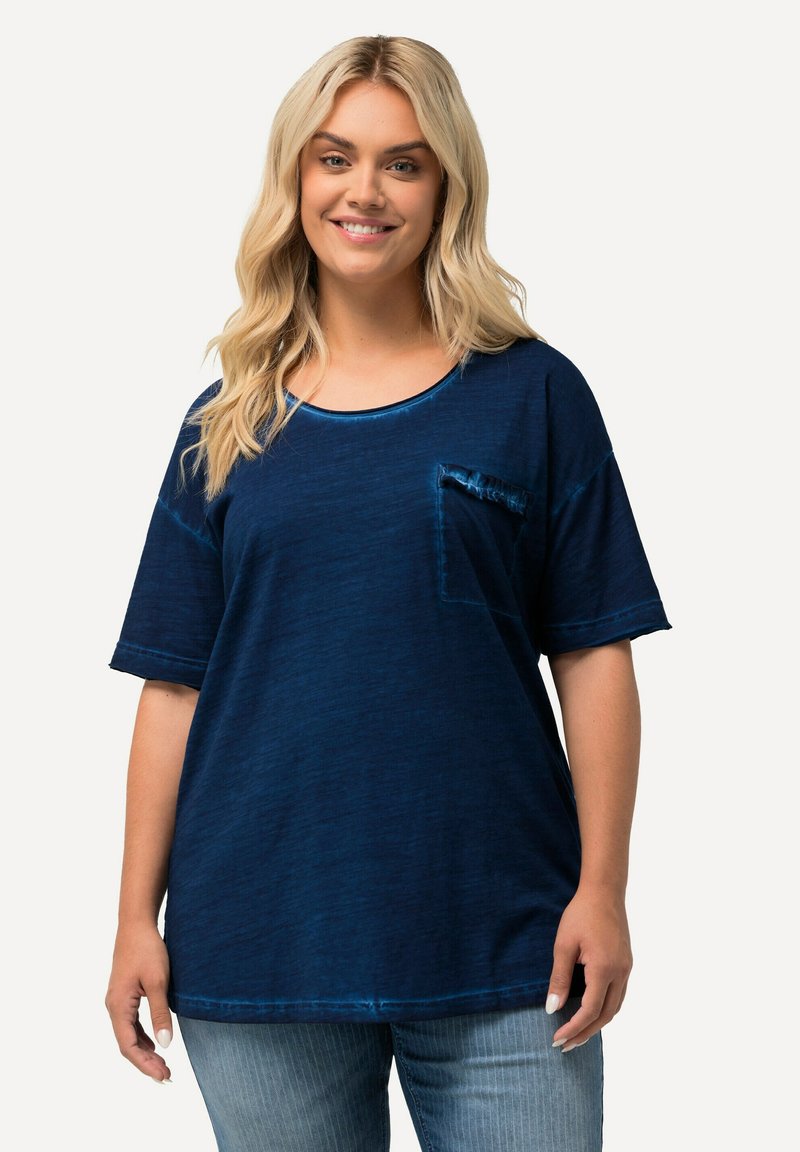Námořnická modrá oversized tričko vyrobené z měkkého materiálu, s kulatým výstřihem, krátkými rukávy a malou přední kapsou s volánovým okrajem.