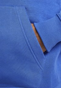 Blå sweatshirts med en blød tekstur, en kængurulomme og ribbede ærmer. Materialet virker let og behageligt.