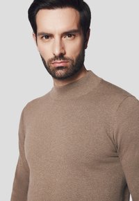 Brązowy sweter dziany z wysokim dekoltem, dopasowanym krojem i gładką strukturą, z długimi rękawami i subtelnymi detalami szycia.