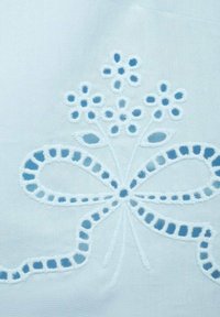 Tessuto bianco con motivo floreale ricamato blu e un fiocco. I dettagli includono anelli e punti, e una texture liscia e morbida.