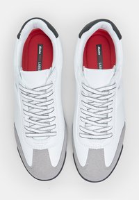 Fehér bőr sneakers szürke velúr részletekkel, szürke fűzőkkel és piros talpbetéttel. Gumi talp a tapadáshoz és a támogatáshoz.