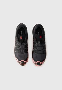 Baskets noires de sport avec des accents roses, dotées d'un dessus texturé, d'un design élégant et d'une semelle extérieure en caoutchouc distinctive. Système de laçage intégré à l'avant.