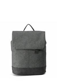 Mochila de tela gris con acabado texturizado, solapa plegable y parte inferior de cuero negro. Incluye un asa superior y una etiqueta con el logo en la parte frontal.