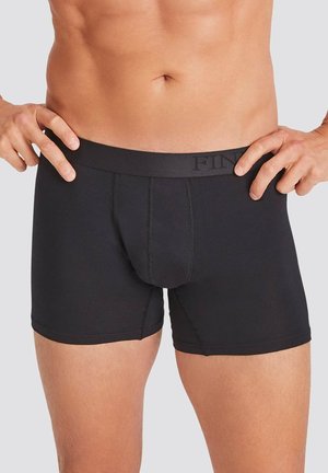 Schwarze Baumwoll-Boxershorts mit enger Passform, ausgestattet mit einem markierten Bund und detaillierter Nahtverarbeitung, entworfen für Komfort und Unterstützung.