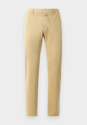 Beige chinos med slim passform og glat bomuldsstof. Har en lynlås i gylpen, bæltestropper og minimale syninger.