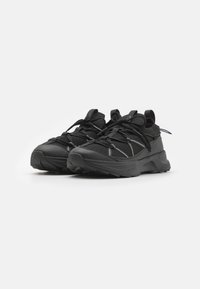 Chaussures de sport noires avec une tige texturée, un système de laçage proéminent, un bout renforcé et une semelle robuste pour une adhérence et une stabilité optimales.