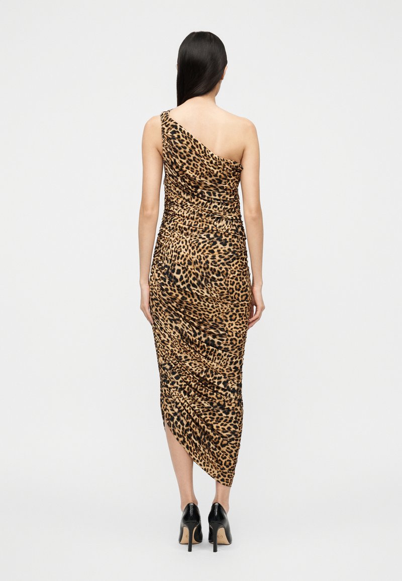 Robe longue à imprimé léopard, à une épaule, avec une texture froncée. Silhouette ajustée et ourlet asymétrique, associée à des talons noirs.