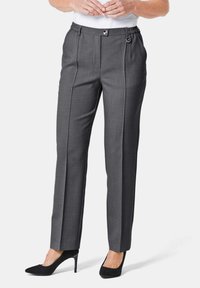 Grau maßgeschneiderte Hose mit glatter Textur, elastischem Bund, vorderen Falten und einem dekorativen Ringdetails. Kombiniert mit schwarzen High Heels.