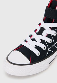 Mustad musta kanvaasist kõrge profiiliga sneaker, millel on valged paelad, kontrastne punane õmblus, kummist varbakattega ja tekstuuriga valge tallaga, millel on diamandi muster.